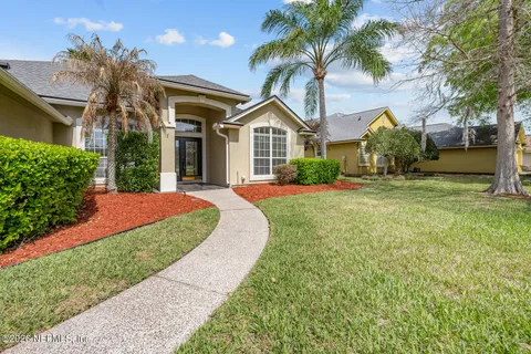 a front view of a house with a yard and potted plants