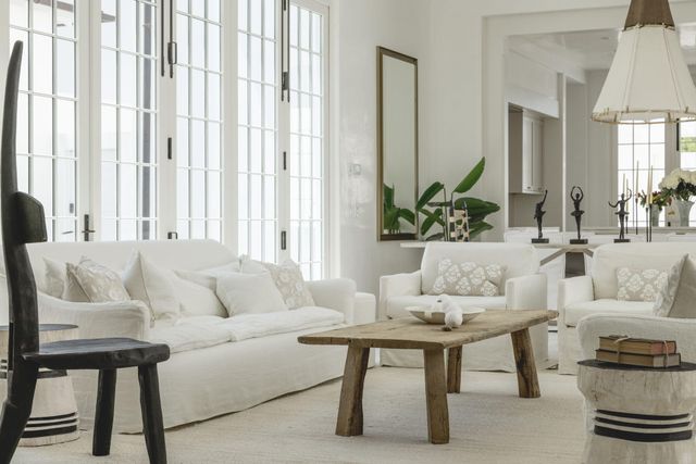 a room with lots of white furniture and a large window