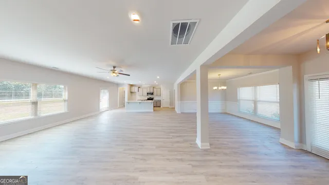 a view of a big room with windows and chandelier fan
