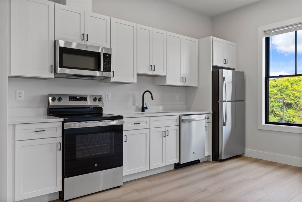 198 Albion Street, Unit 202 Wakefield, MA 01880 - Photo 3 of 13 a kitchen with stainless steel appliances granite countertop a stove a refrigerator and a microwave