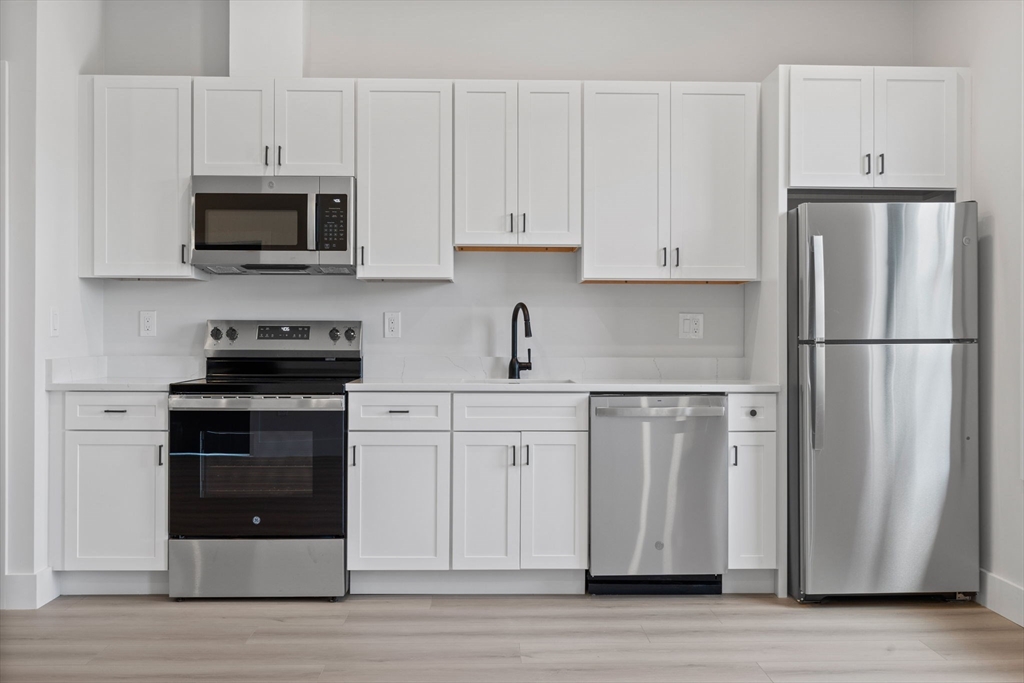 198 Albion Street, Unit 202 Wakefield, MA 01880 - Photo 4 of 13 a kitchen with stainless steel appliances granite countertop a refrigerator stove a sink and white cabinets