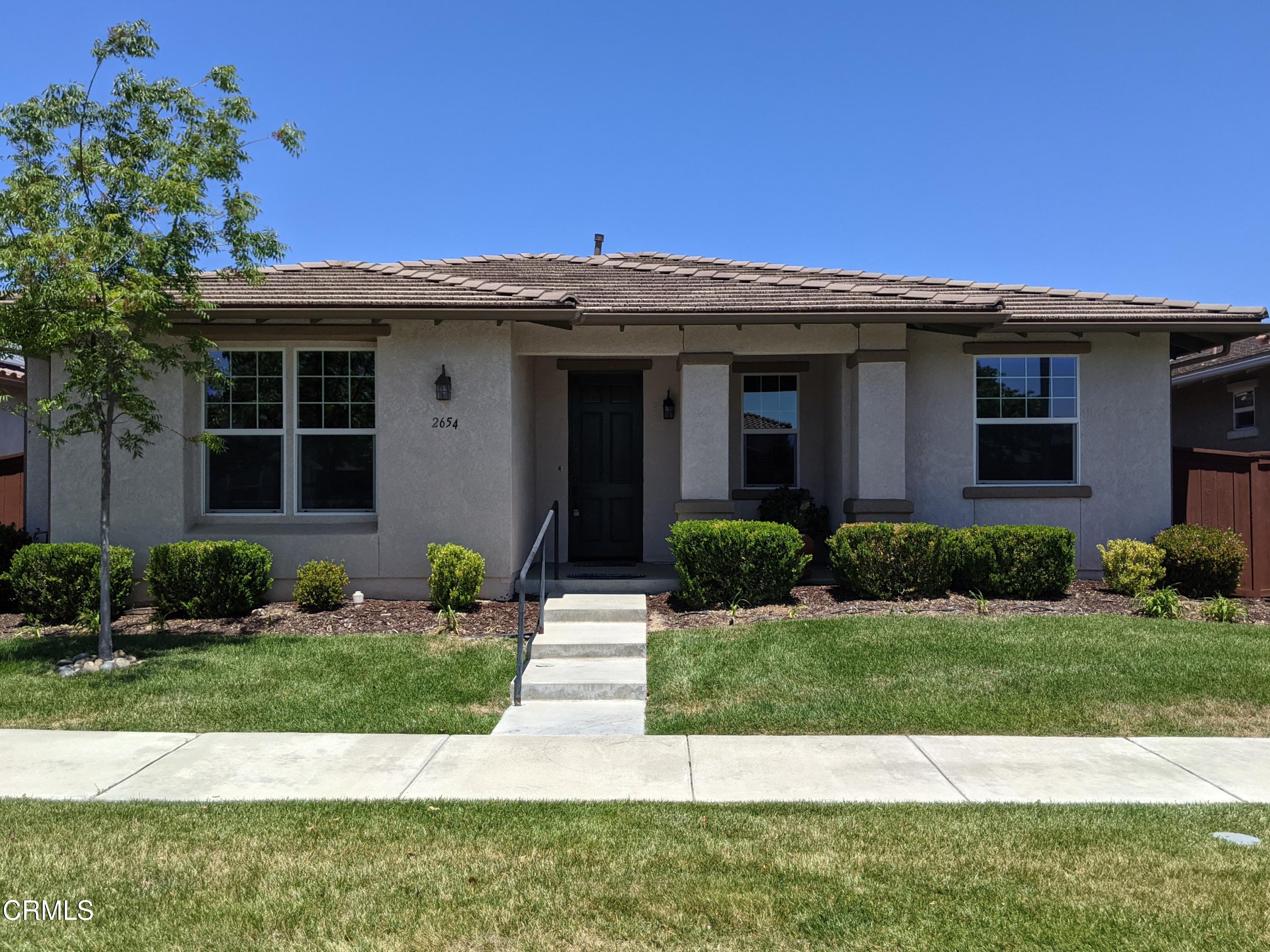 a view of a white house with a yard and potted plants