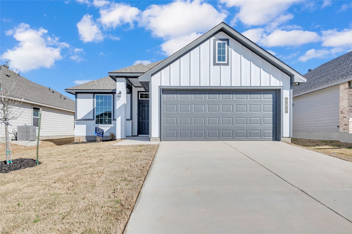 121 Walk Way Jarrell, TX 76537 - Photo 1 of 29 View of front of house with a front lawn, driveway, cooling unit, board and batten siding, and a garage