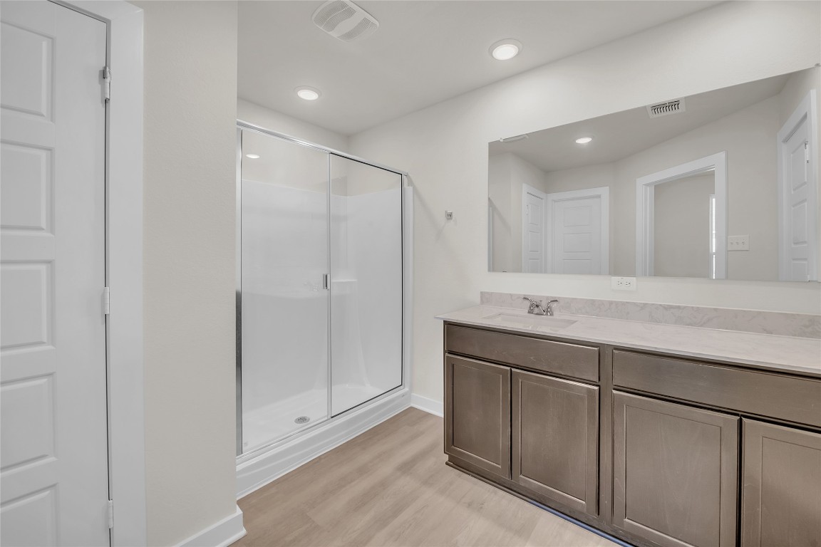 121 Walk Way Jarrell, TX 76537 - Photo 11 of 29 Full bath with visible vents, a stall shower, vanity, and wood finished floors