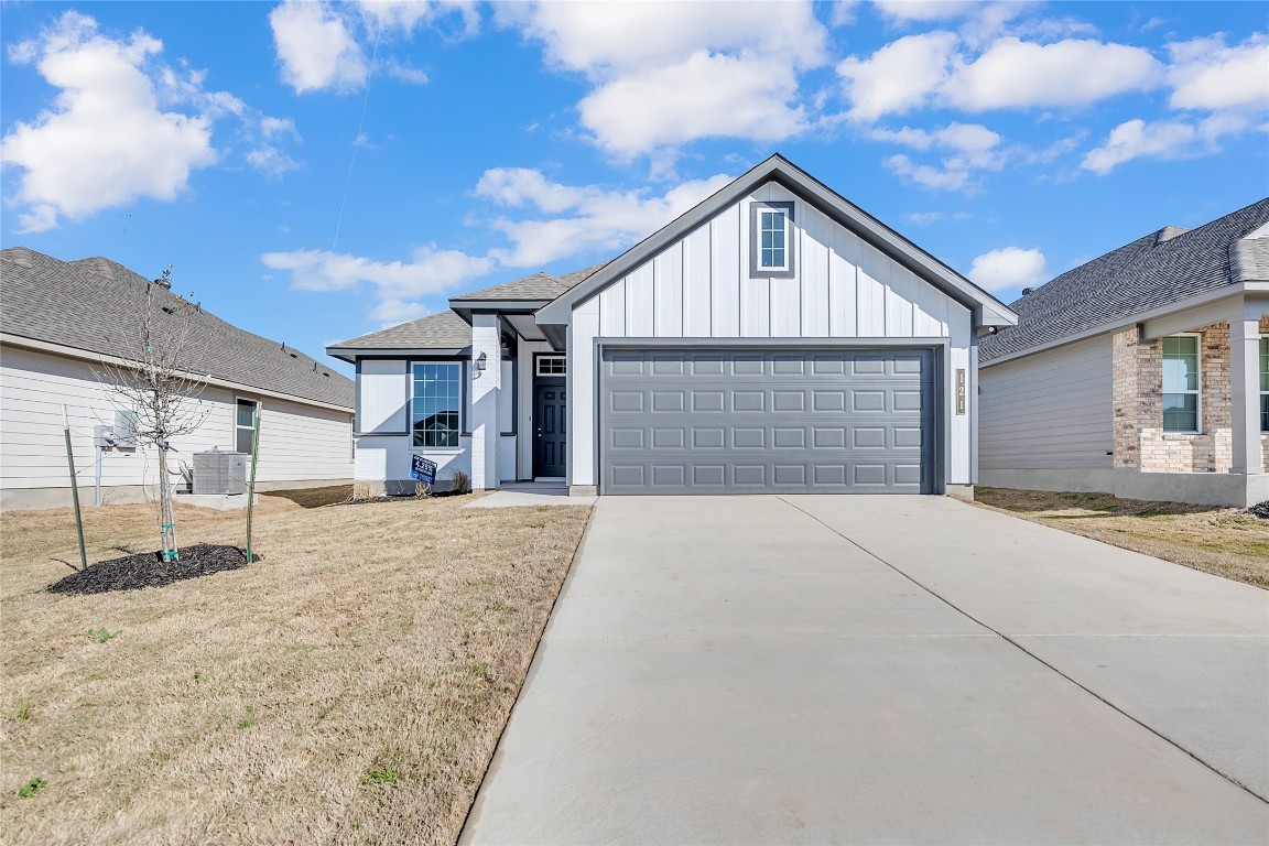 121 Walk Way Jarrell, TX 76537 - Photo 2 of 29 View of front of property with board and batten siding, a front lawn, central AC unit, a garage, and driveway