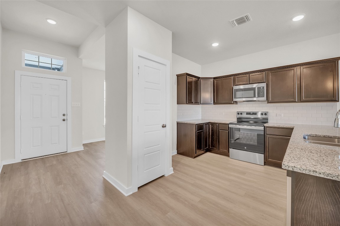 121 Walk Way Jarrell, TX 76537 - Photo 21 of 29 Kitchen featuring visible vents, a sink, stainless steel appliances, light wood-style floors, and dark brown cabinetry