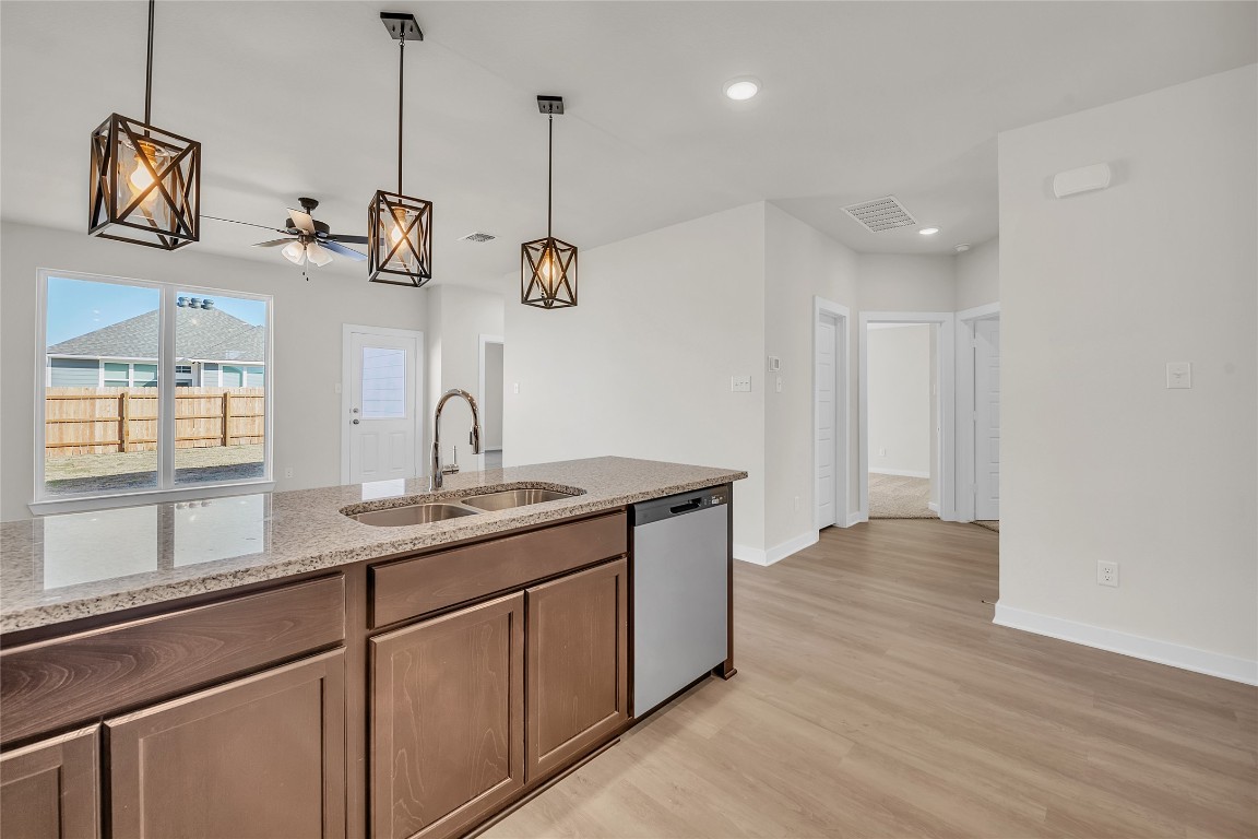 121 Walk Way Jarrell, TX 76537 - Photo 23 of 29 Kitchen featuring visible vents, a sink, light stone counters, light wood-style floors, and dishwasher