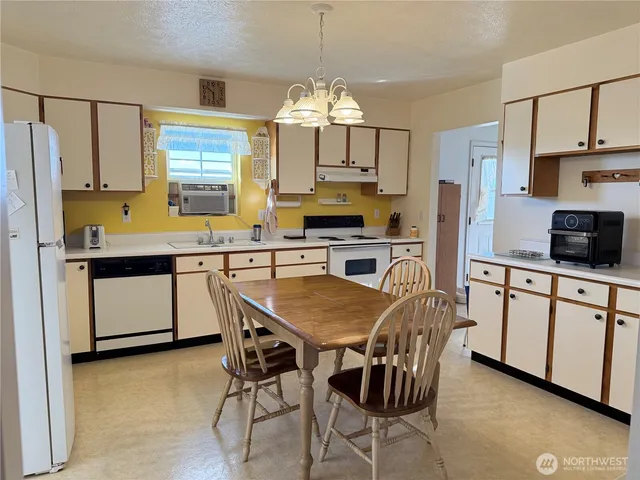 a kitchen with stainless steel appliances granite countertop a stove a sink a microwave a refrigerator a dining table and chairs