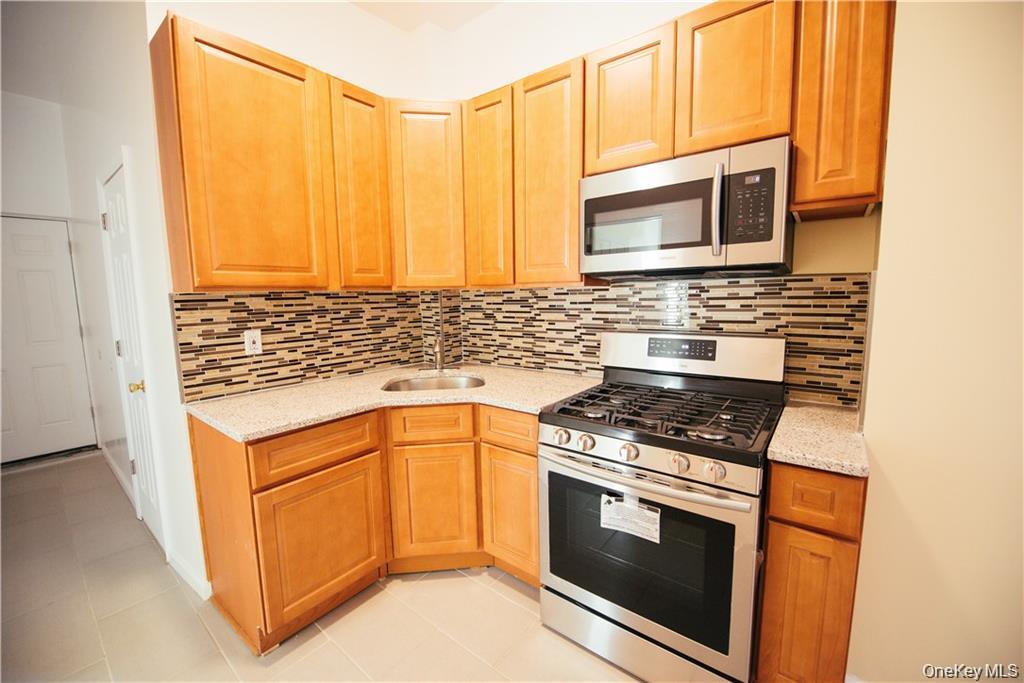1443 Beach Avenue Bronx, NY 10460 - Photo 11 of 25 a kitchen with stainless steel appliances granite countertop a stove and a microwave
