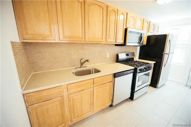 a utility room with stainless steel appliances white cabinets and a sink