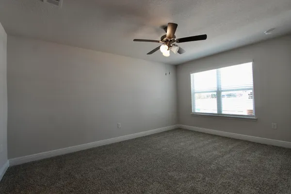 an empty room with a window and a fan