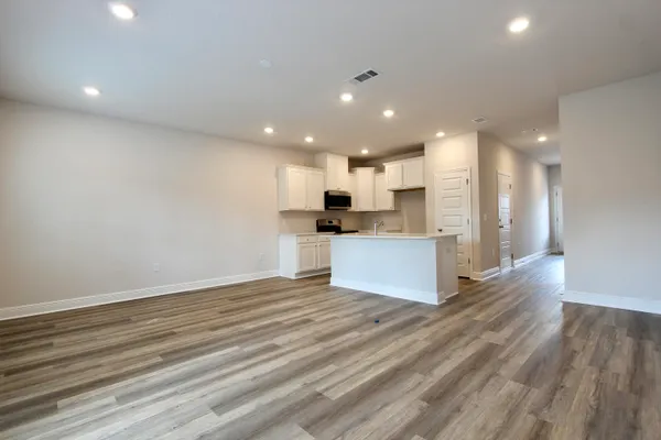 a view of kitchen with kitchen island wooden floor center island and stainless steel appliances