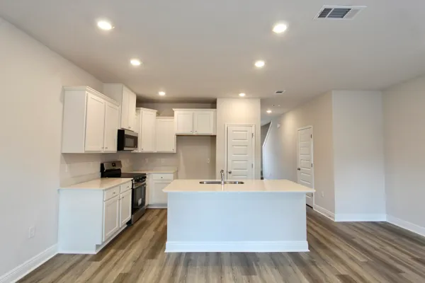 a large kitchen with a large counter top a sink stainless steel appliances and cabinets