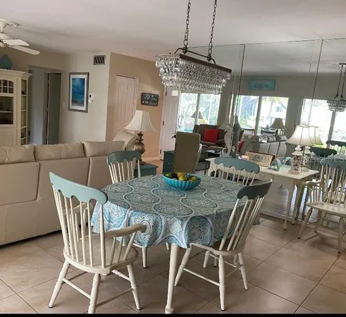 a living room with furniture a chandelier and kitchen view