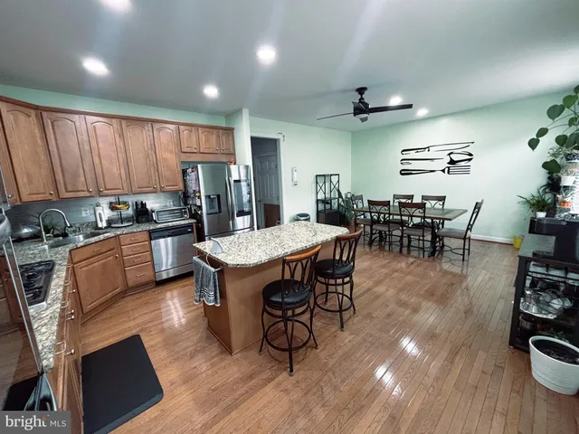 an open kitchen with kitchen island wooden floor and stainless steel appliances