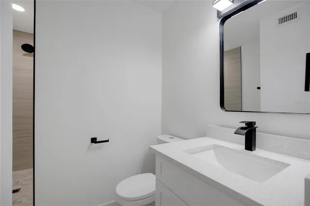 a bathroom with a granite countertop sink mirror vanity and toilet