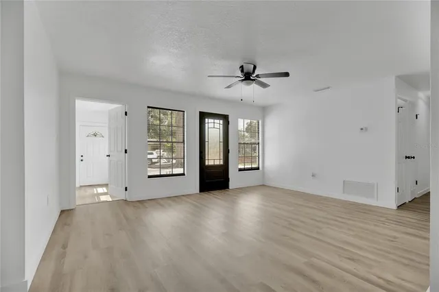 a view of an empty room with a window and wooden floor