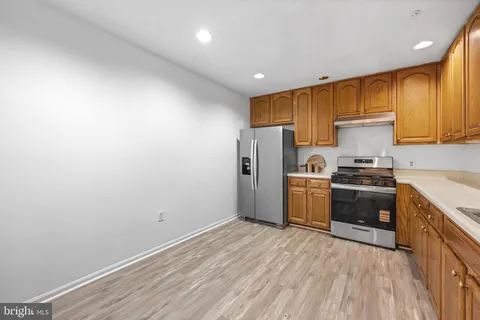 a kitchen with granite countertop a refrigerator and a stove top oven