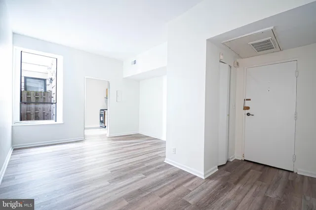 a view of an empty room with wooden floor and a window