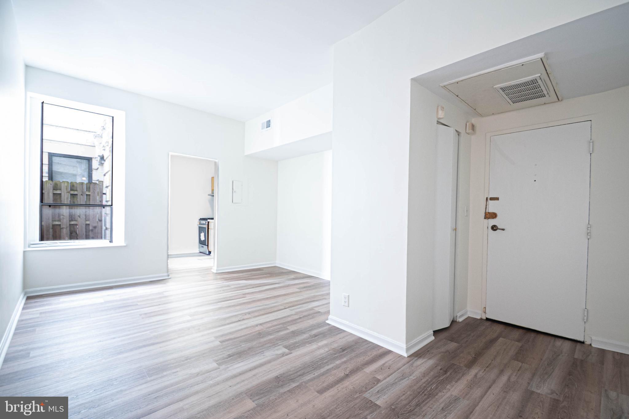 1669 Columbia Road Northwest, Unit 109 Washington, DC 20009 - Photo 13 of 35 a view of an empty room with wooden floor and a window