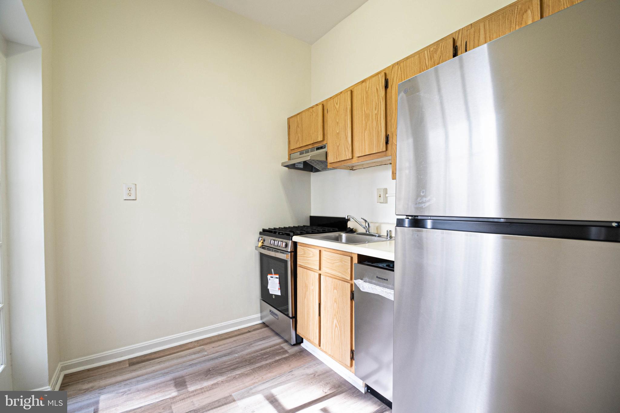 1669 Columbia Road Northwest, Unit 109 Washington, DC 20009 - Photo 16 of 35 a kitchen with stainless steel appliances a refrigerator and a stove top oven
