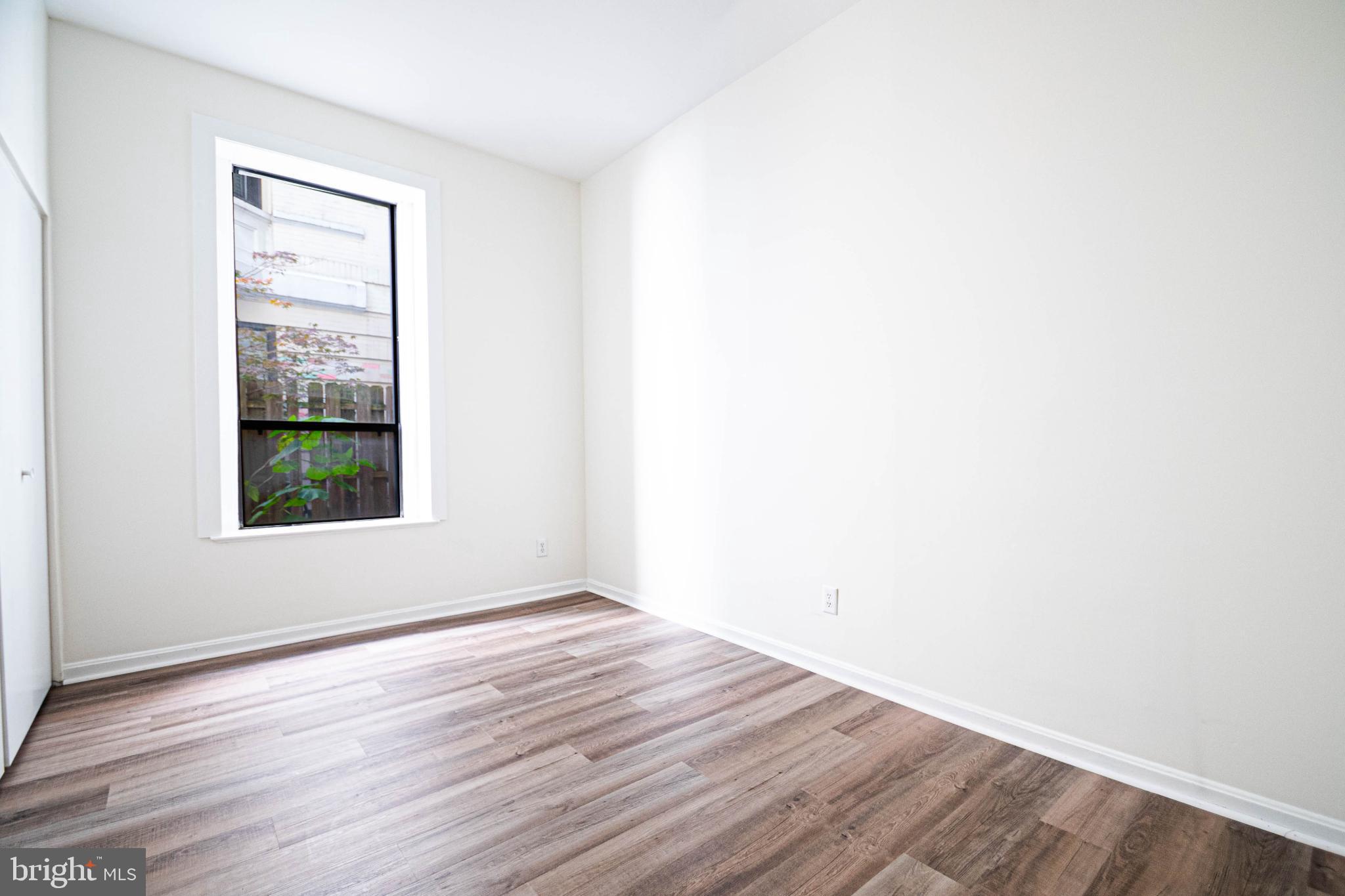 1669 Columbia Road Northwest, Unit 109 Washington, DC 20009 - Photo 27 of 35 a view of an empty room with wooden floor and a window