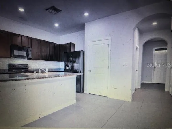 a kitchen with stainless steel appliances granite countertop a refrigerator and a stove top oven
