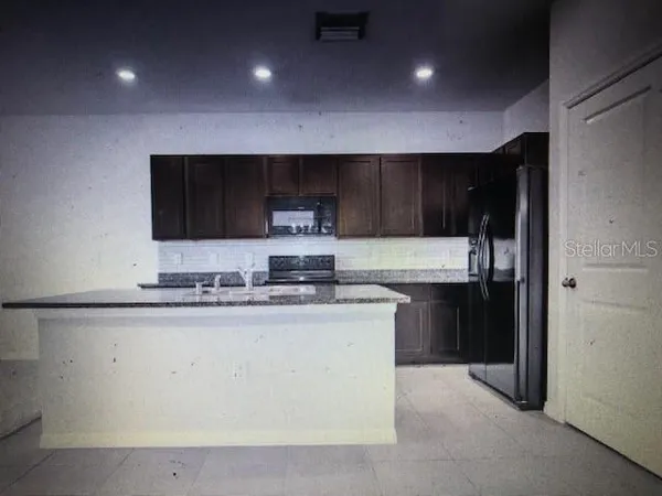 a kitchen with stainless steel appliances granite countertop a stove a sink and a refrigerator with wooden floor