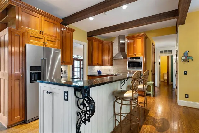 a kitchen with stainless steel appliances granite countertop a stove top oven a sink a dining table and chairs with wooden floor