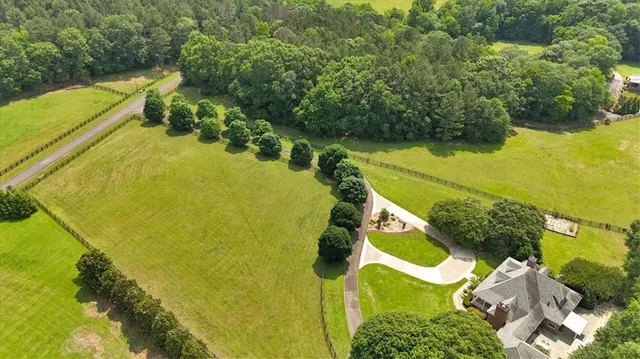 an aerial view of a residential houses with outdoor space and trees all around