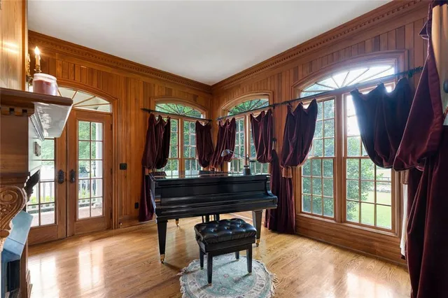 a bedroom with a bed couch and a large window with wooden floor