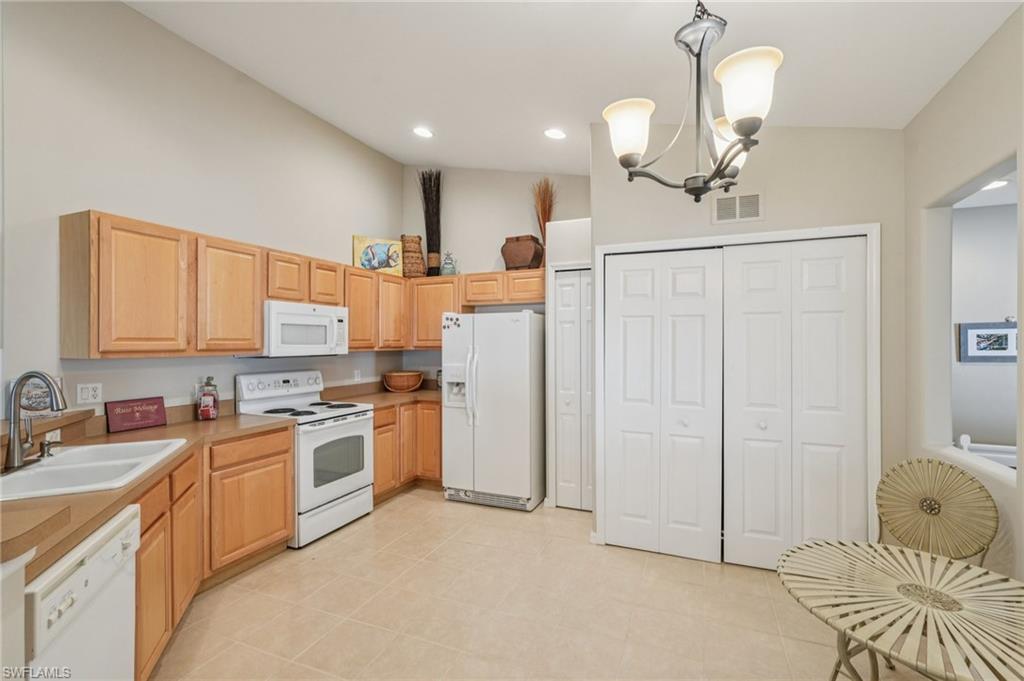 9583 Hemingway Lane, Unit 4309 Fort Myers, FL 33913 - Photo 5 of 18 a large white kitchen with a stove a sink a refrigerator and a chandelier