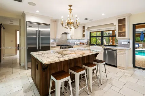 a kitchen with granite countertop stainless steel appliances a island table and chairs in it