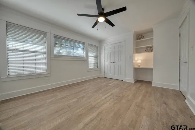 a view of empty room with wooden floor and fan