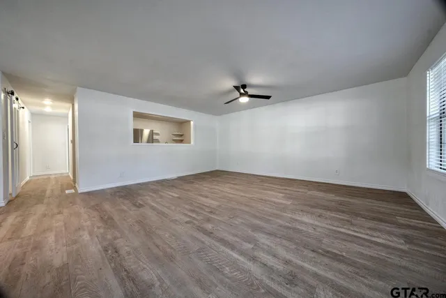 a view of an empty room with a window and wooden floor