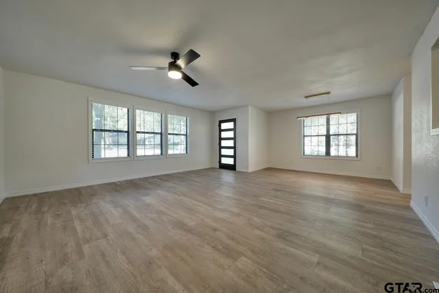 a view of an empty room with a window and wooden floor