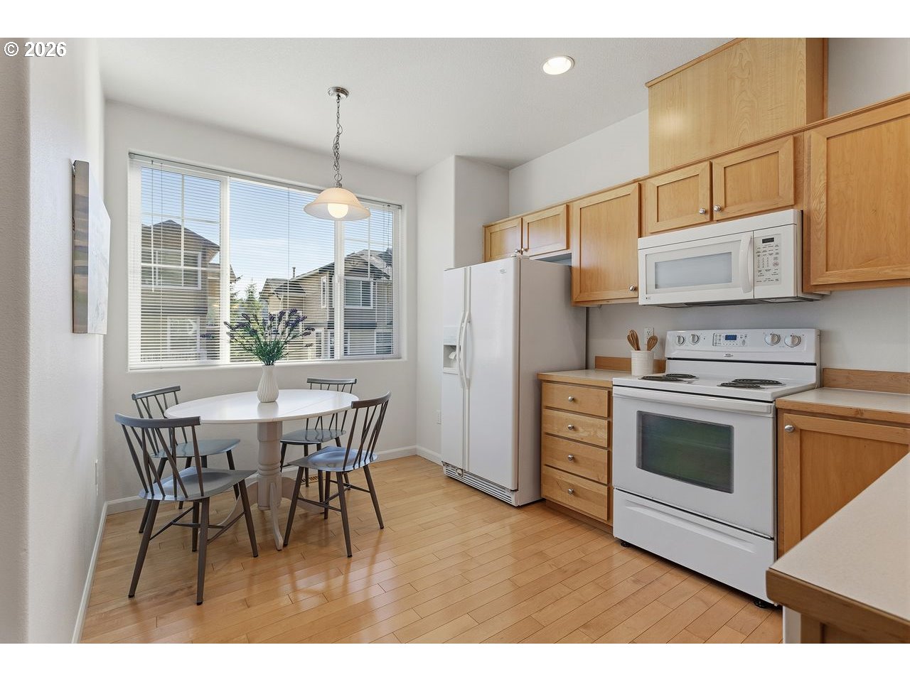 15450 Southwest Sparrow Loop, Unit 102 Beaverton, OR 97007 - Photo 10 of 27 a kitchen with stainless steel appliances granite countertop a stove a refrigerator a microwave a dining table and chairs with wooden floor