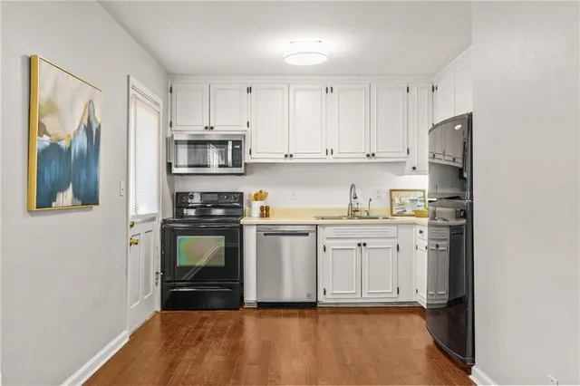 a kitchen with granite countertop a refrigerator stove and white cabinets
