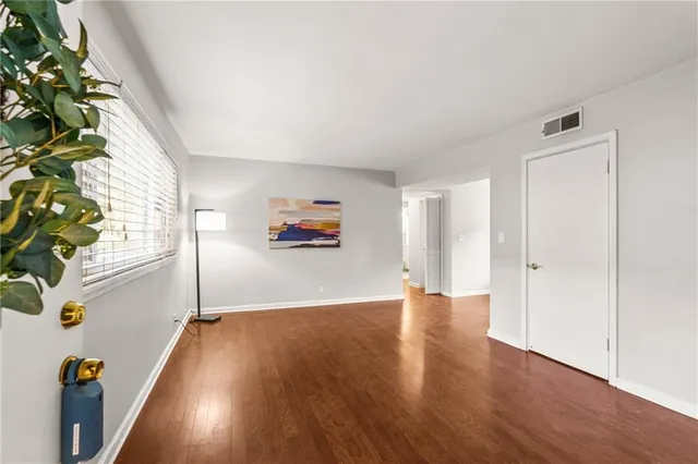 an empty room with wooden floor and windows