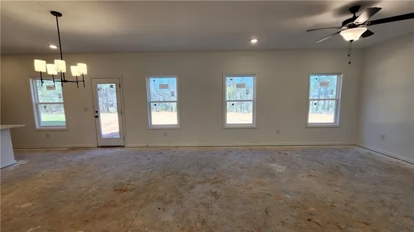 a view of an empty room with window and chandelier fan