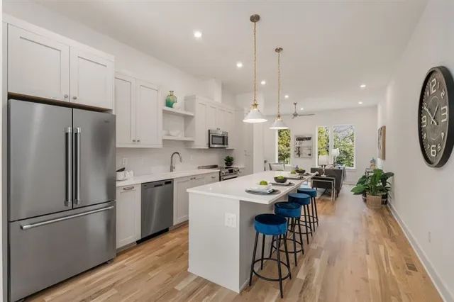 a kitchen with a refrigerator a stove a sink a dining table and chairs with wooden floor