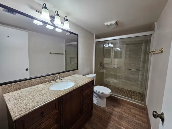 a bathroom with a granite countertop sink toilet a mirror a vanity and shower