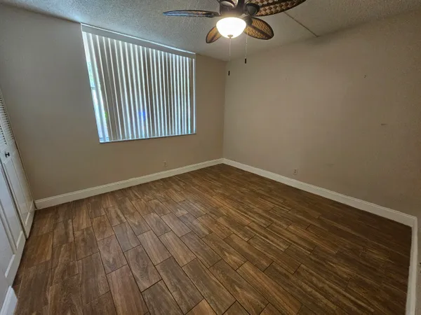an empty room with wooden floor fan and windows