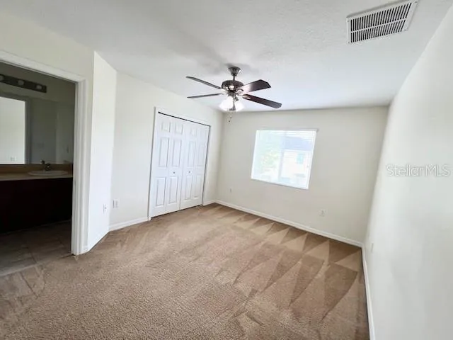 an empty room with windows and fan
