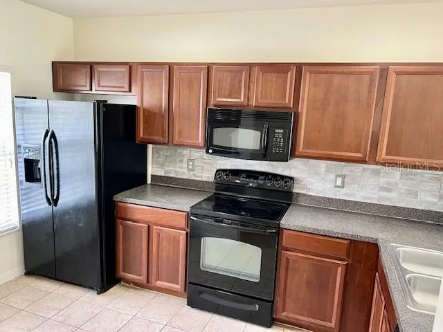 a kitchen with granite countertop a refrigerator stove and microwave