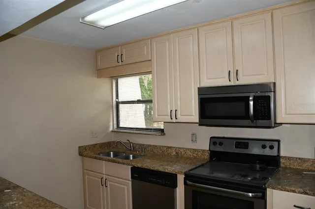 a kitchen with granite countertop white cabinets and black appliances