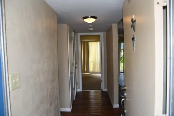 a view of a hallway with wooden floor and a bathroom