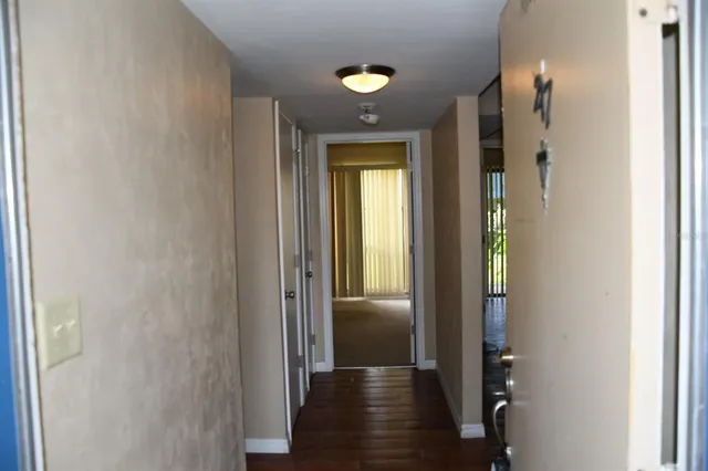 a view of a hallway with wooden floor and a bathroom