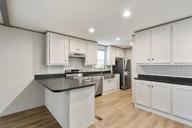 a kitchen with white cabinets appliances and sink