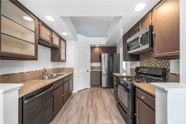 a kitchen with stainless steel appliances granite countertop a stove a sink and a refrigerator